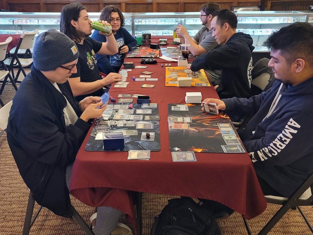 Players mid-game at a long table of Magic matches
